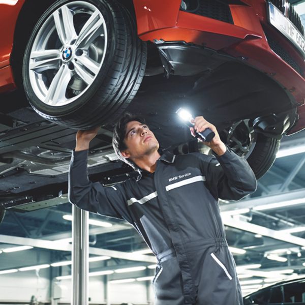 a man looking underneath a red bmw